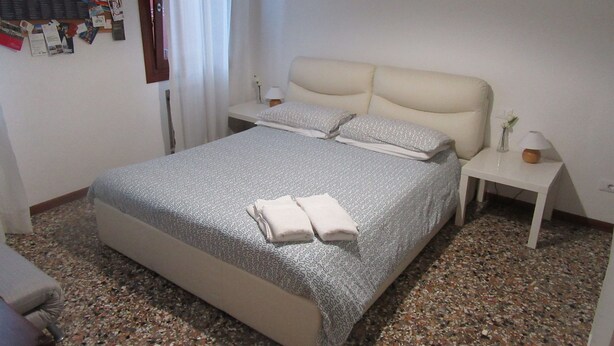 Une chambre d’hôtel bien aménagée, avec un grand lit, deux tables de chevet et un petit bureau.