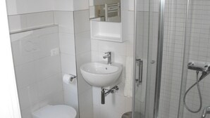 Une petite salle de bain avec des toilettes, un lavabo et une douche.