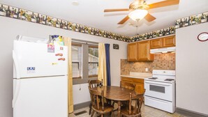A compact kitchen with a refrigerator, stove, and wooden dining table. - 2 Bedroom 1 Bath Cottage (Knoxville)