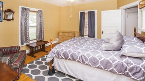 A bedroom with a bed, a ceiling fan, a dresser, a chair, and a window with curtains. - 2 Bedroom 1 Bath Cottage (Knoxville)