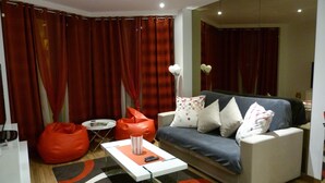Un salon moderne avec un canapé, des fauteuils en forme de sac de haricots rouges, une table basse et un téléviseur.