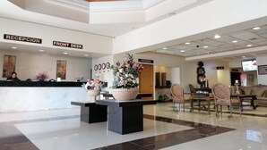 Zona de recepción de un hotel con mostrador de recepción y cartel indicador.