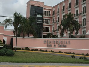 Un bâtiment rose avec une enseigne indiquant « RESIDENCIAL Inn & Suites ».