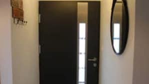 A closed door with a handle, a small mirror on the wall, and a light fixture above the door.