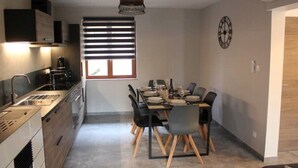A modern kitchen with a dining area, featuring a built-in oven, a coffee machine, and a dining table set for four.