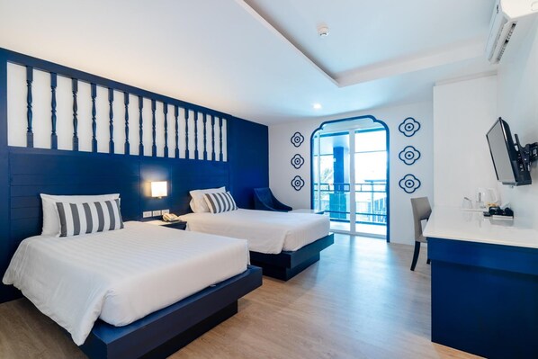 Habitación de hotel con dos camas, un escritorio y vistas al exterior.