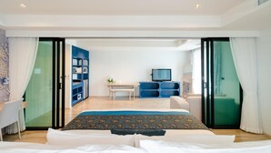 A modern hotel room with a bed, a desk, a TV, and a sliding door leading to a balcony. - Bhukitta Boutique Hotel - SHA Plus (PHUKET)