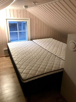 Una habitación con cama, ventana y paredes de madera.