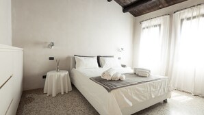 A bedroom with a large bed, two bedside tables, a nightstand, and a window with curtains. - Elegant Modern Design Home. Campo dei Mori. Air Conditioning. Wifi. (Venezia)