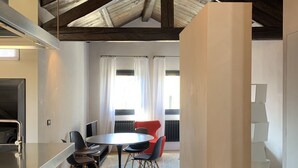 A modern kitchen with a bar area, a dining table with chairs, and a red chair in the background. - Elegant Modern Design Home. Campo dei Mori. Air Conditioning. Wifi. (Venezia)