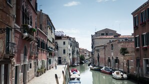 A narrow canal in a historic European town with buildings on both sides, boats docked along the water, and a clear sky above. - Elegant Modern Design Home. Campo dei Mori. Air Conditioning. Wifi. (Venezia)