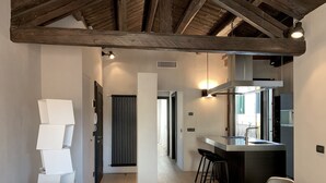 A modern kitchen with a built-in microwave, a dining area with a round table and chairs, and a hallway leading to a bedroom with a large window. - Elegant Modern Design Home. Campo dei Mori. Air Conditioning. Wifi. (Venezia)