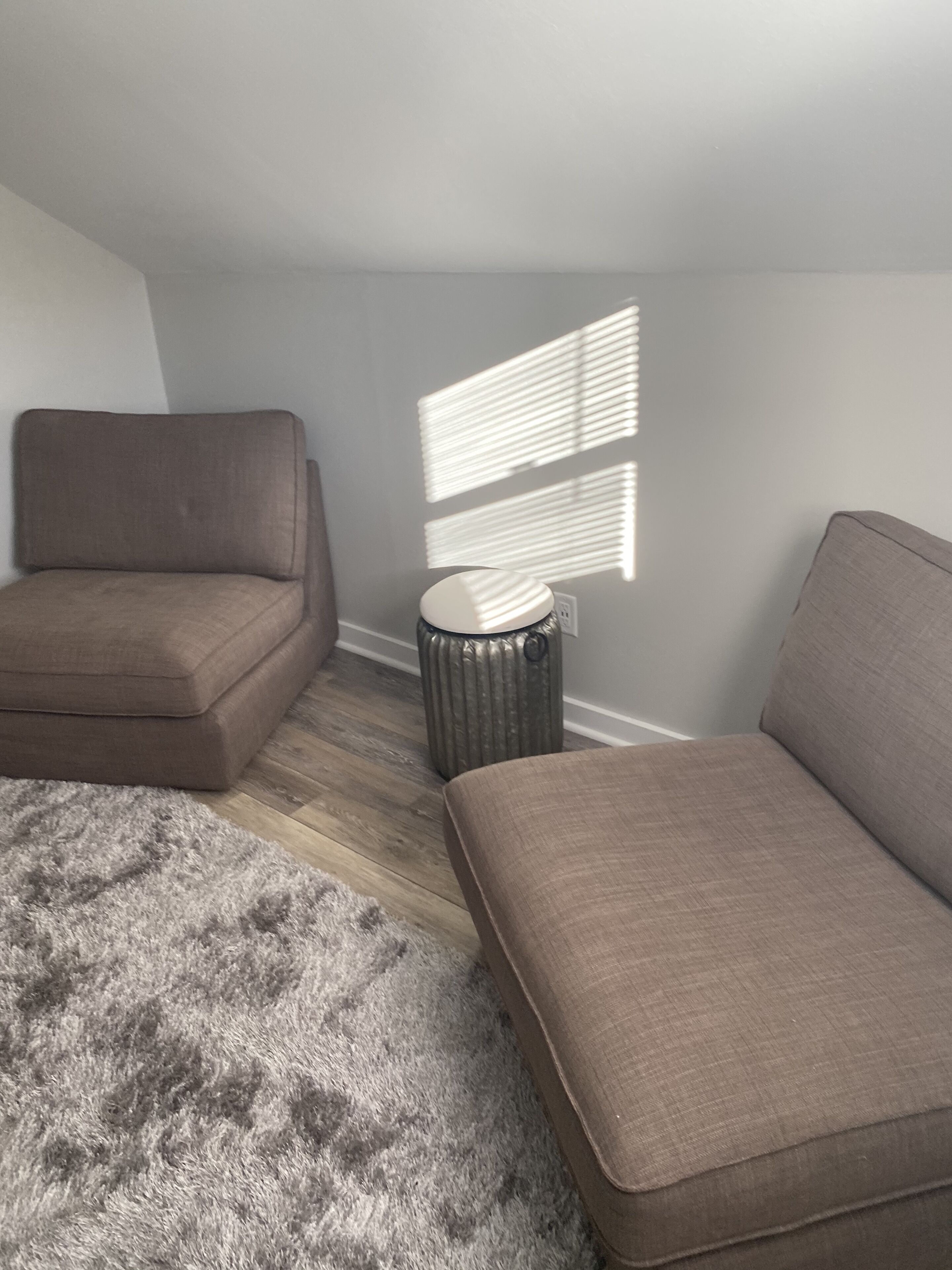 A room with a brown sofa, a small round table, and a patterned rug.