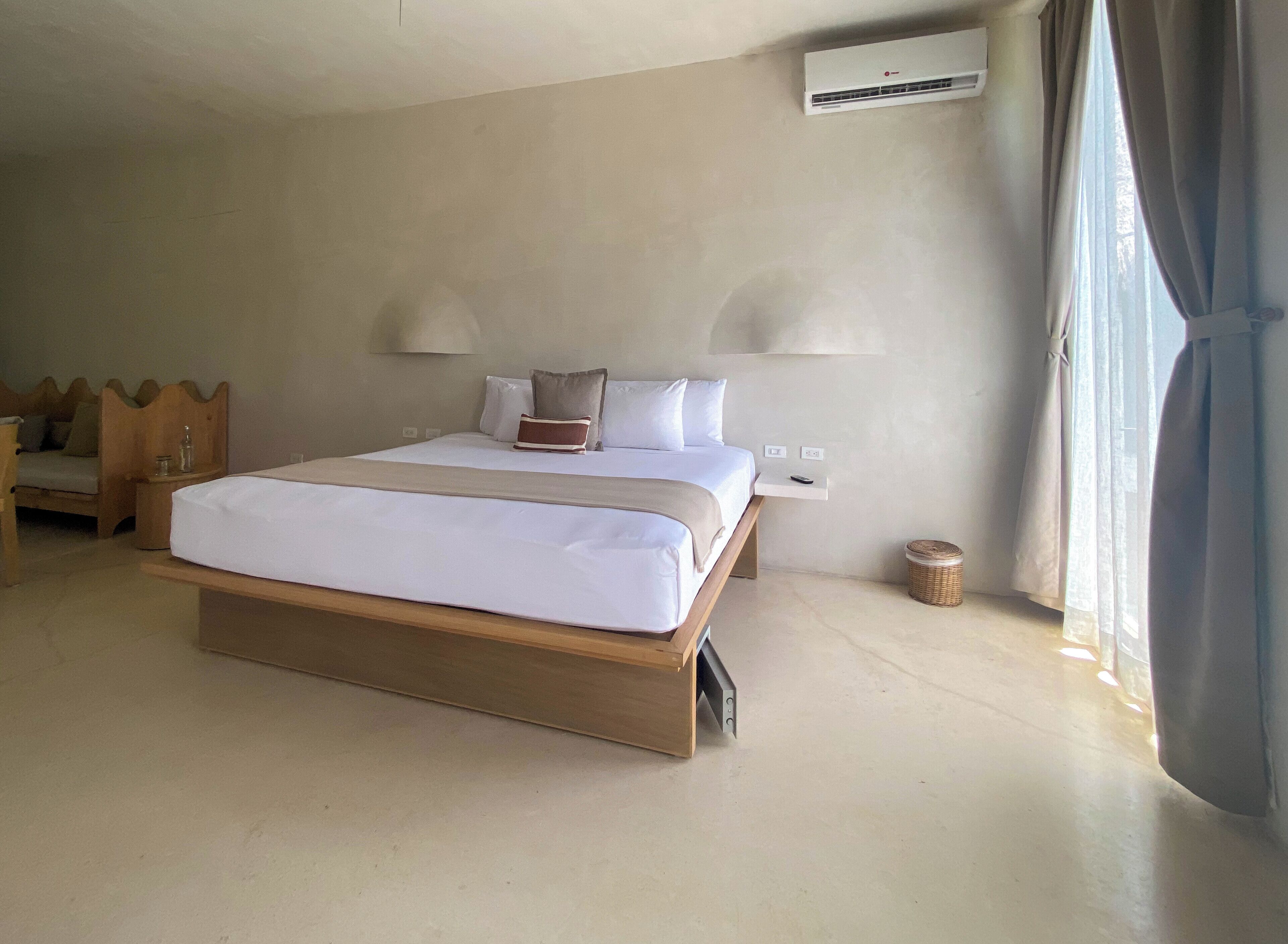 Quarto de hotel com uma cama grande, abajures, ar condicionado e vista para o exterior através de uma janela.