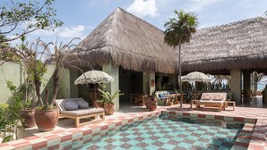 A pool area with checkered tiles, lounge chairs, and potted plants. - Hotel Panamera (Tulum)