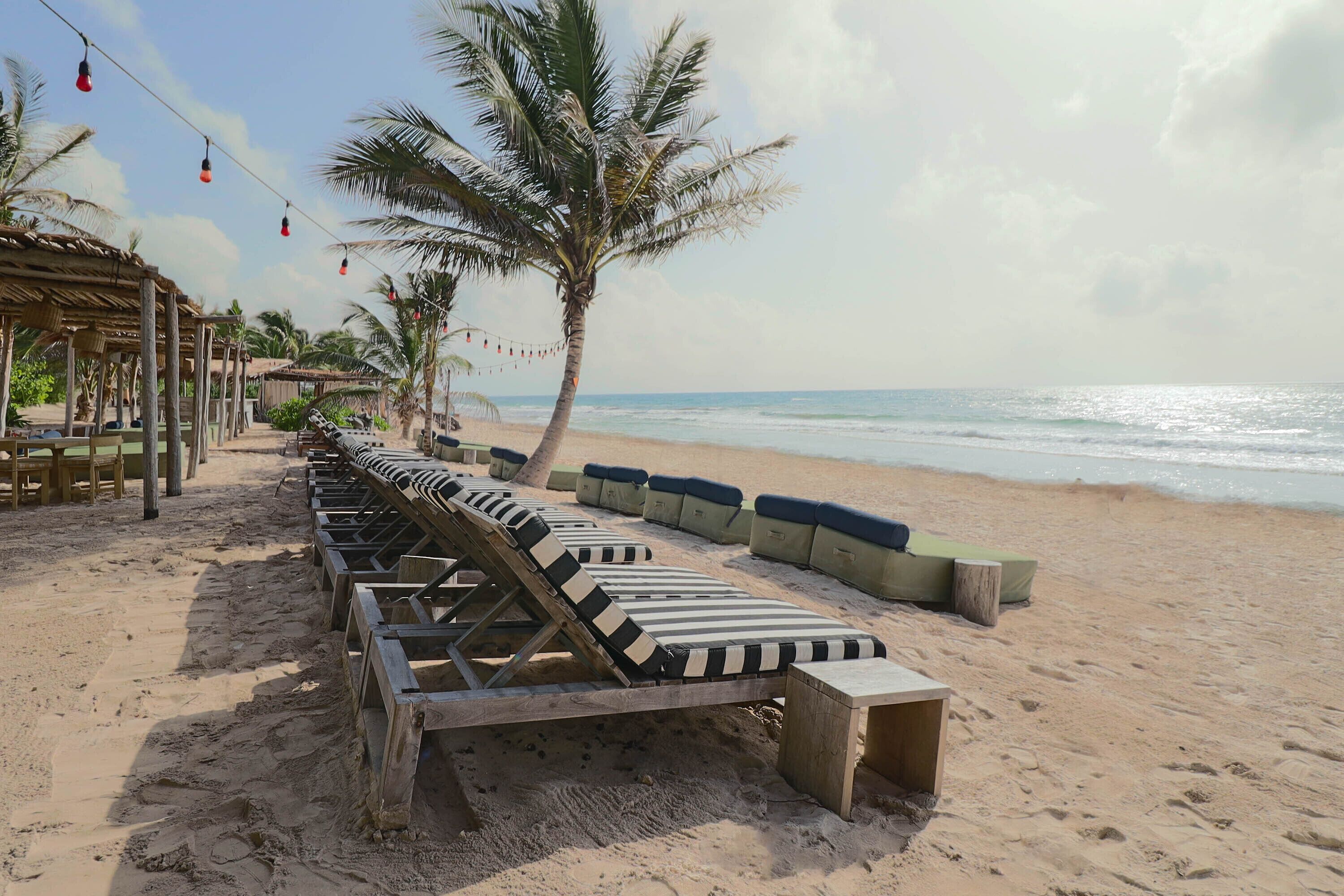 A beachside lounge area with sun loungers and a wooden deck, overlooking the ocean.
