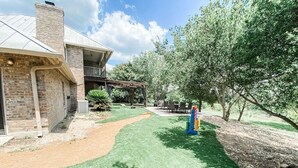 Una casa amb façana de maó, un porxo cobert i un jardí ben cuidat.