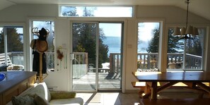 Un'ampia stanza con una grande porta scorrevole in vetro che dà su un terrazzo, un tavolo di legno e una panca.