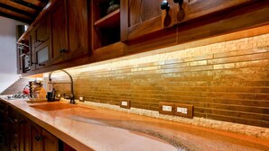 A kitchen with wooden cabinets, a built-in brick backsplash, and a granite countertop.
