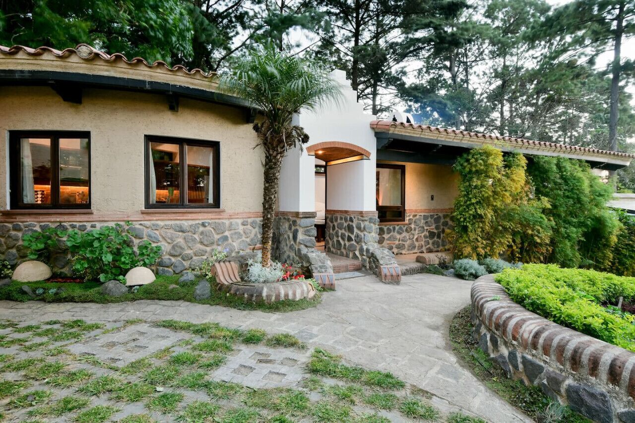 Een huis met stenen muren, een gebogen dak en een geplaveid pad naar de ingang.