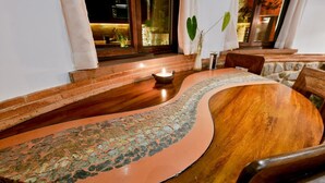 A round wooden table with a unique mosaic inlay design, accompanied by chairs and a candle.