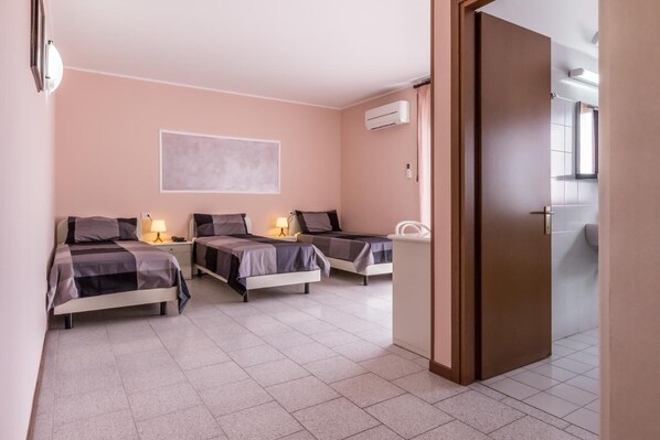 A hotel room with two beds, a wall-mounted air conditioner, and a large window. - Hotel Maris (Sala Baganza)