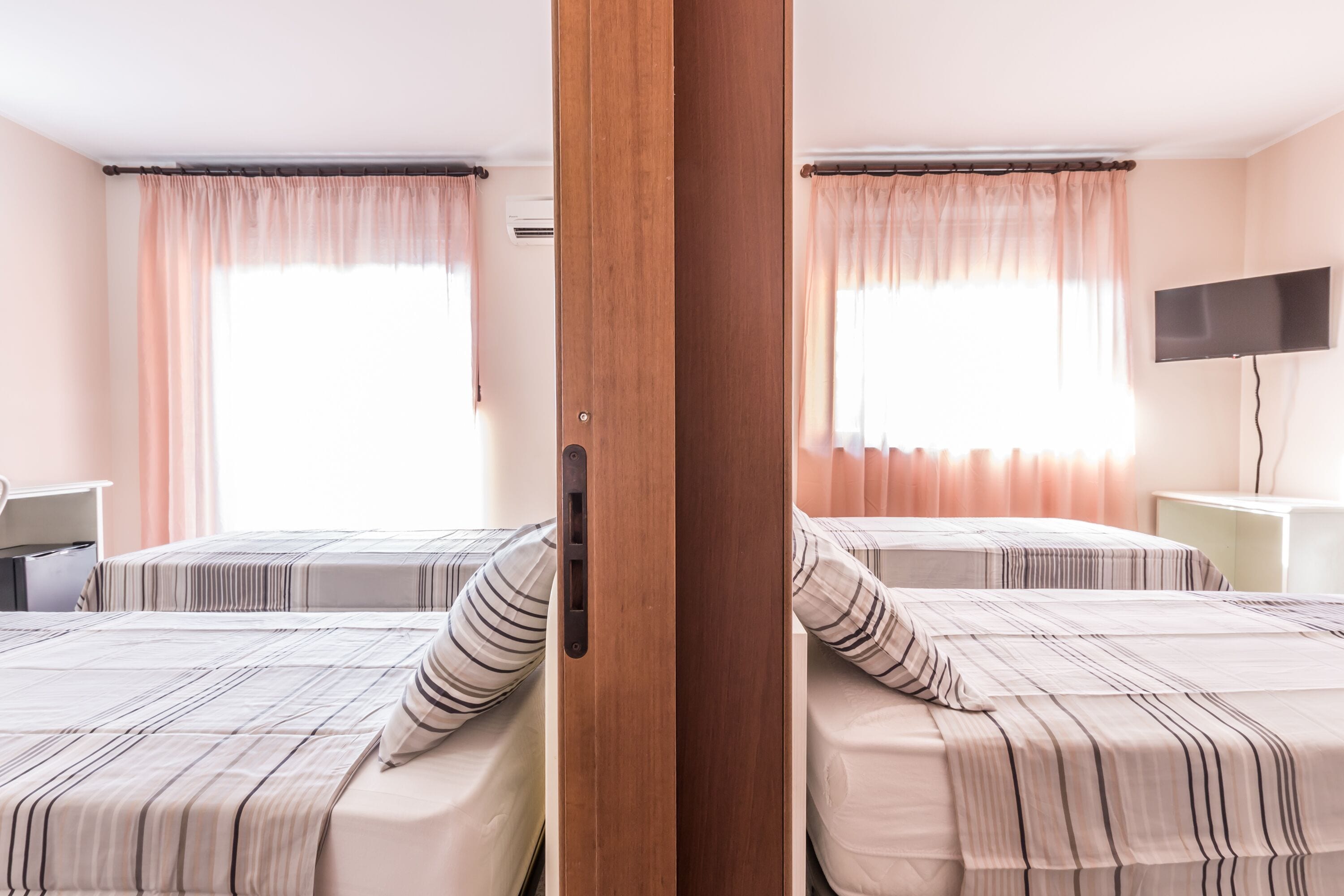 Ein Hotelzimmer mit zwei Betten, einem Fernseher und einem Schreibtisch.