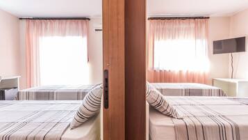 Ein Hotelzimmer mit zwei Betten, einem Fernseher und einem Schreibtisch.