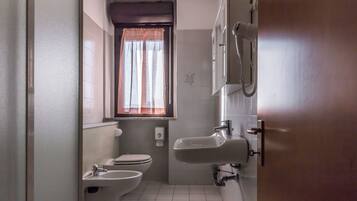 Une petite salle de bain comprenant des toilettes, un bidet et un lavabo.