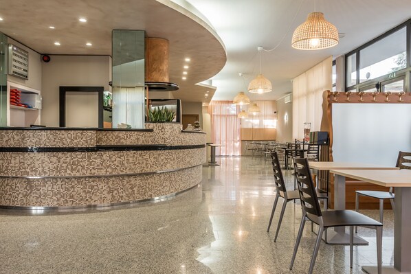 A modern hotel lobby with a curved reception desk, seating area, and large windows. - Hotel Maris (Sala Baganza)