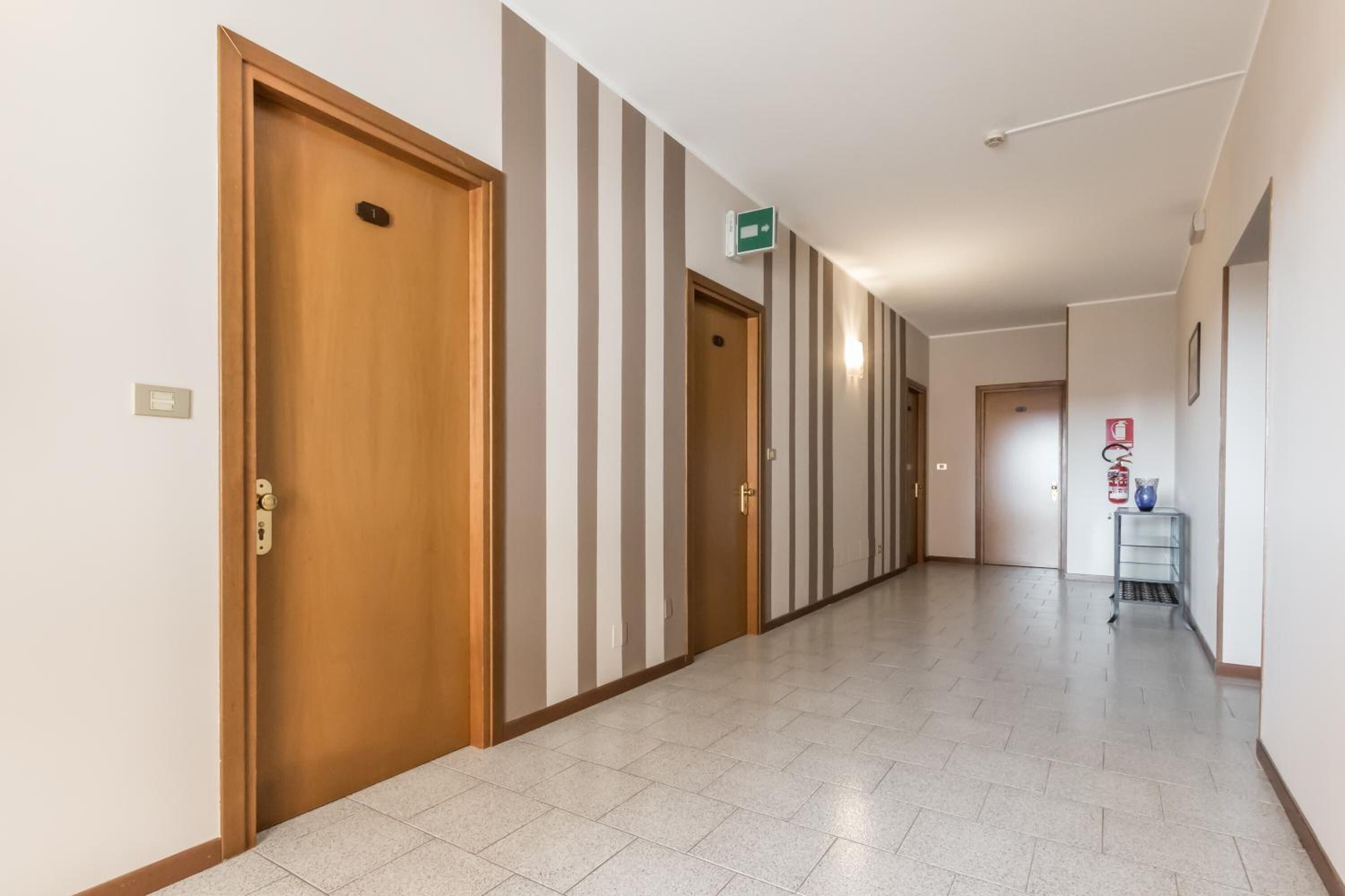 A hallway with doors, striped walls, and a fire extinguisher.