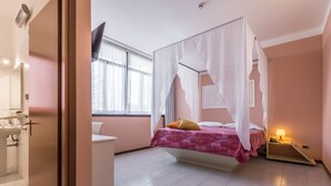 Une chambre à coucher comprenant un lit, une table de chevet, une commode, une fenêtre et une salle de bain avec un lavabo et un miroir.