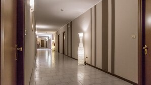 Un couloir d’hôtel avec des portes des deux côtés, un luminaire et un détecteur d’incendie.