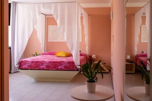A bedroom with a four-poster bed, a bedside table, a nightstand, and a potted plant. - Hotel Maris (Sala Baganza)