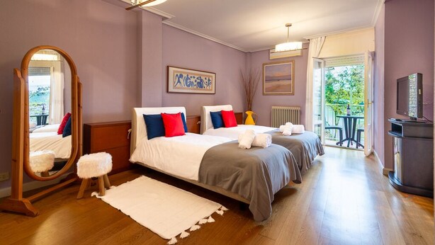A bedroom with two beds, a mirror, a dresser, a radiator, and a TV. - VIRGEN DEL VALLE APARTMENT. -WINE ROUTE- 4 PEOPLE- 75M² (Cenicero)