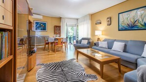 A living room with a sofa, coffee table, and zebra rug. There is a dining area with a table and chairs, and a kitchen area with cabinets and a refrigerator. - VIRGEN DEL VALLE APARTMENT. -WINE ROUTE- 4 PEOPLE- 75M² (Cenicero)