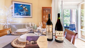 A dining table set with plates, glasses, and a bottle of wine, with a framed painting and a window view in the background. - VIRGEN DEL VALLE APARTMENT. -WINE ROUTE- 4 PEOPLE- 75M² (Cenicero)