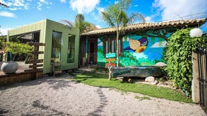Una casa con fachada verde y un mural de un pájaro en el lateral, con un letrero que dice 'RECEPCAO'.