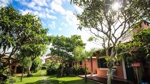 Un patio con un sendero de piedra, abundante vegetación y un edificio con fachada roja.