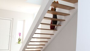 Un escalier moderne avec des marches en bois et un vase rempli de fleurs sur la plateforme.