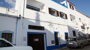 Un bâtiment blanc avec des bordures bleues et un panneau indiquant qu’il est interdit de se garer.
