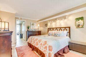 A bedroom with a large bed, a wooden headboard, a nightstand, a dresser, and a bench.