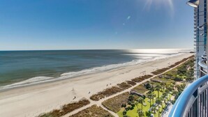 Uitzicht op het strand vanaf een hoog hotel met een heldere lucht en zon.