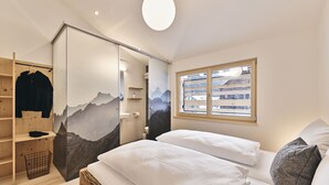 Une chambre avec un lit, une armoire, une fenêtre et une vue sur les montagnes.