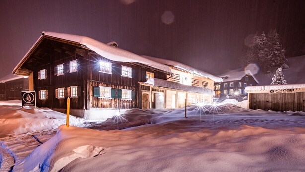 Un bâtiment en bois doté de nombreuses fenêtres et dont le toit est recouvert de neige.