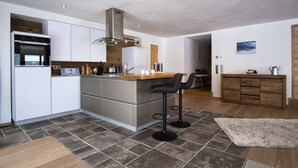 A modern kitchen with a central island, stainless steel appliances, and a wooden dining area.