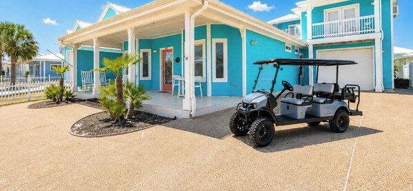 Un edificio costiero con un portico, un carrello da golf e palme.