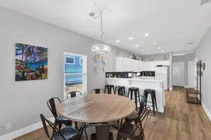 A modern kitchen with white cabinets, a central island, and bar stools.