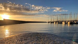 Uma marina com vários veleiros atracados sob um céu ao pôr do sol.