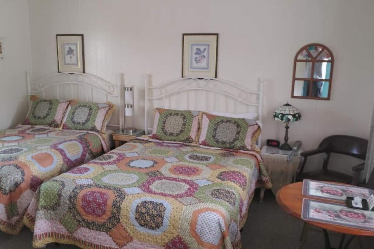 A room with two beds, a small table, and a chair.
